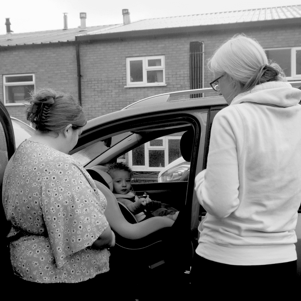 Charlene showing a mum her child safely fitted in a rear-facing car seat